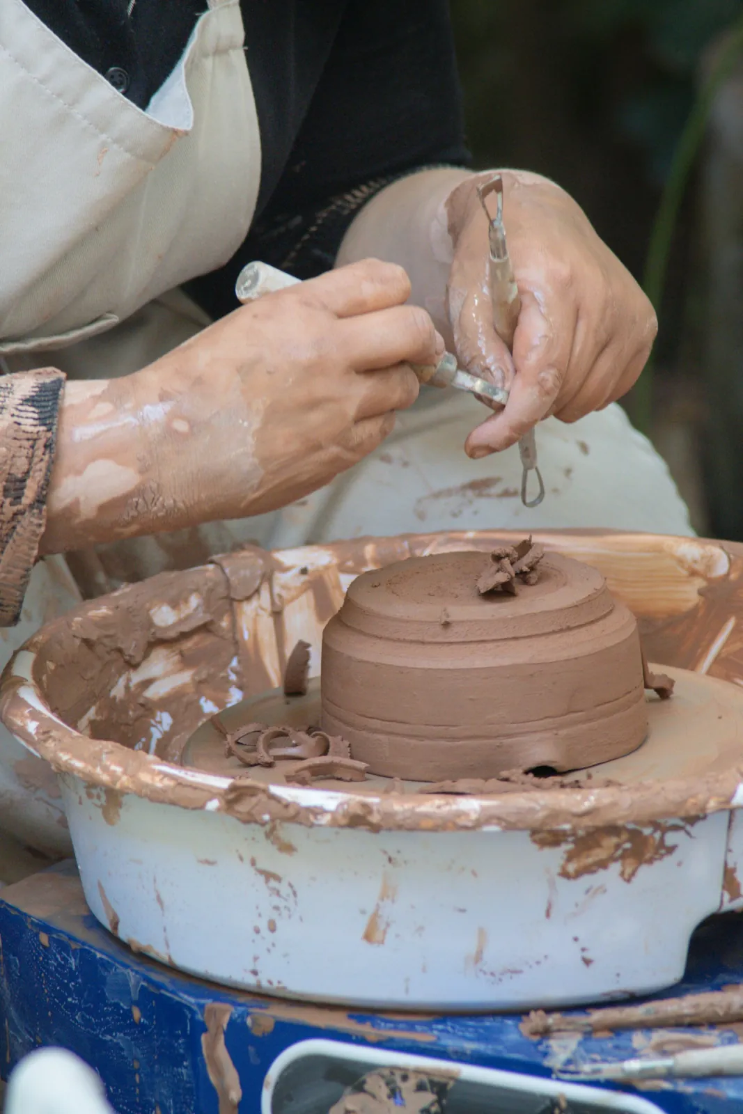 Hands shaping clay on a pottery wheel